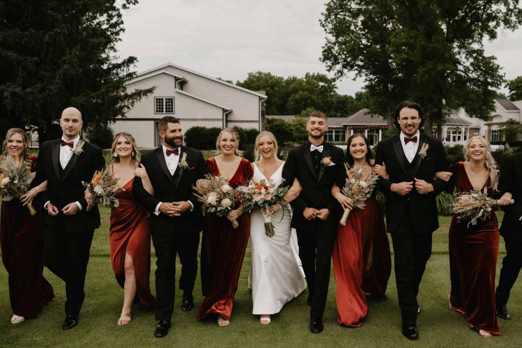 A wedding party walking arm in arm toward the camera